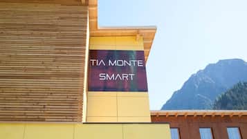 Rakennuksessa on kyltti, jossa lukee ”TIA MONTE SMART”, ja taustalla näkyy vuori.