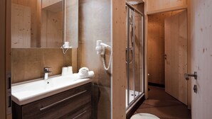 A modern bathroom with a wooden vanity, a large mirror, a shower, and a toilet.
