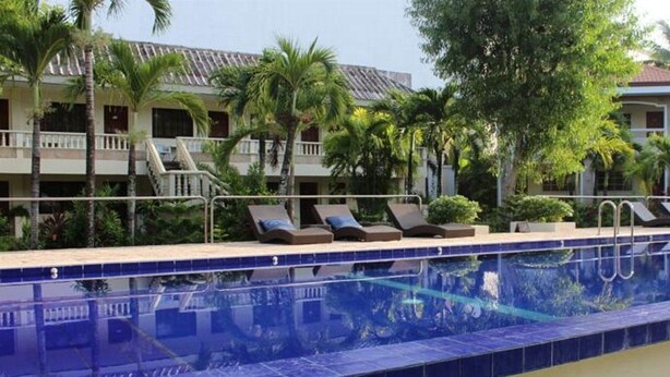 A swimming pool with lounge chairs and palm trees.