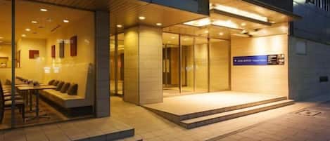 Entrada de hotel con recepción, zona de estar y una escalera que lleva al vestíbulo.