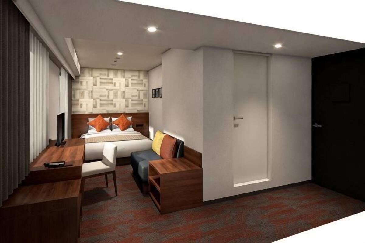 Una habitación de hotel con cama, escritorio, silla, armario y televisor.