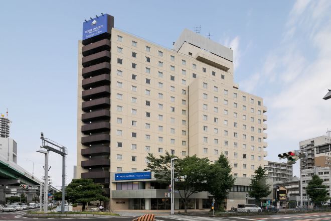 A multi-story hotel with a flat facade, a parking garage, and a clear sky.