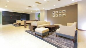 Um lobby moderno com um conjunto de sofás, mesa de centro e quadros na parede.