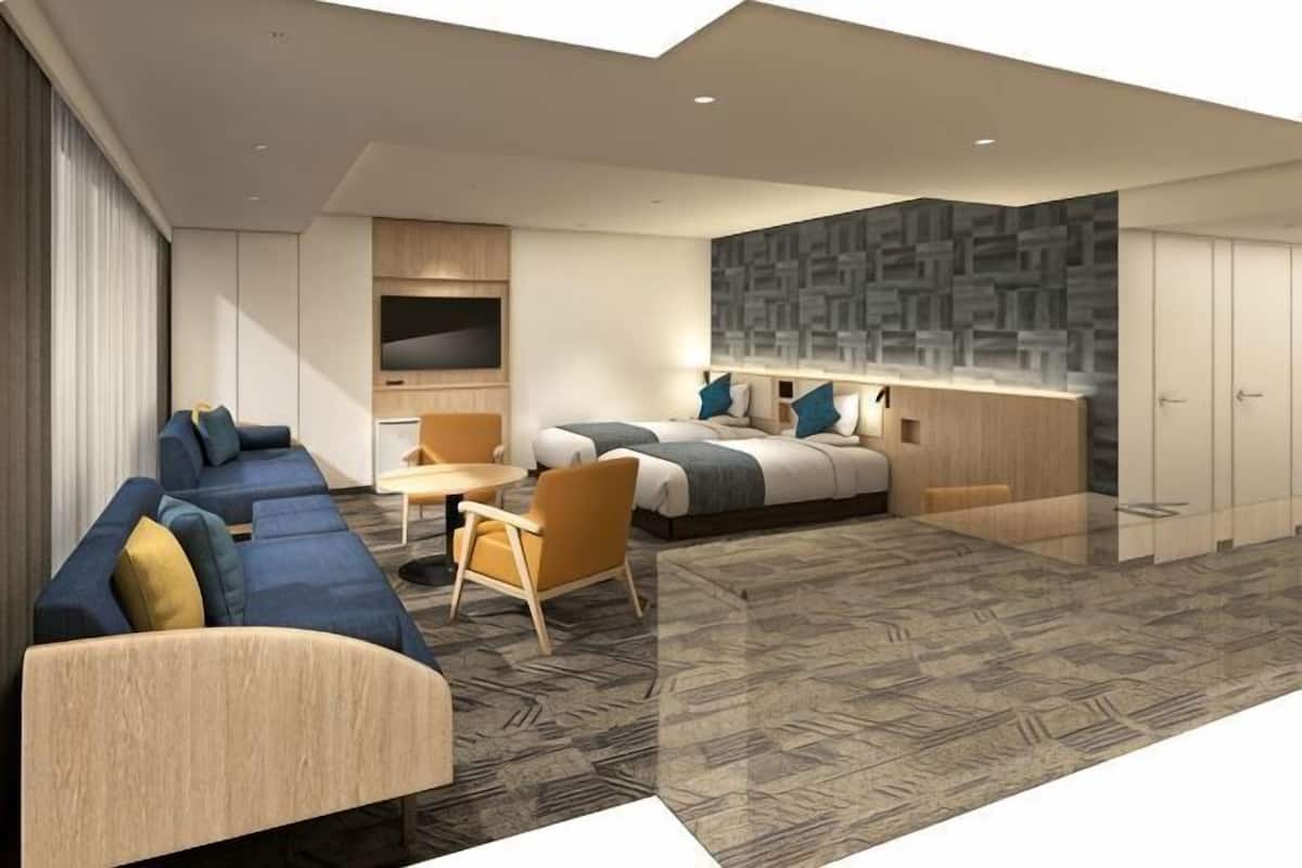 Una habitación de hotel moderna con sofá, cama, escritorio y televisor.