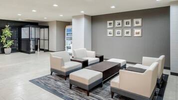 A modern lobby with a seating area, a reception desk, and framed pictures on the wall.