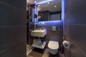 A modern bathroom with a glass shower enclosure, a white sink, and a toilet. - Bluesun Mala Berulia (Brela)