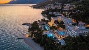 Ein Hotel an der Küste mit Pool, Strand und Bergblick.
