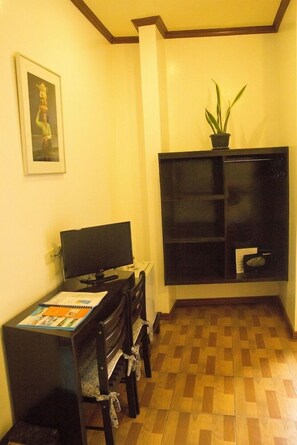 Une pièce comprenant un bureau, un ordinateur, une chaise, une plante en pot et un tableau encadré accroché au mur.