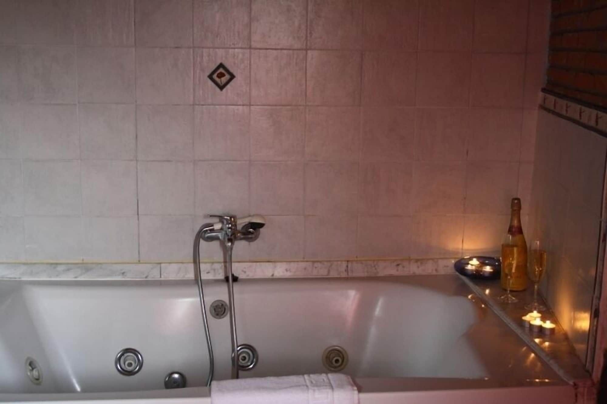 A bathroom with a bathtub, a shower, and a bottle of alcohol on a shelf.