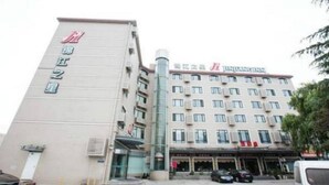 A hotel with a prominent vertical sign on the left and a multi-story building with a flat roof and several windows. - Jinjiang Inn (Shanghai)
