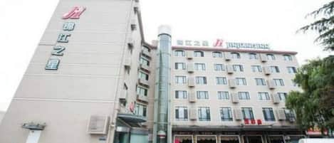 A hotel with a prominent vertical sign on the left and a multi-story building with a flat roof and several windows.