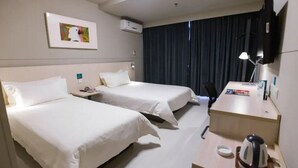 A hotel room with two beds, a desk with a lamp, a coffee maker, and a TV on the wall. - Jinjiang Inn (Shanghai)