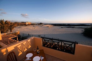 A terrace with a table set for two, overlooking a beach and the sea. - Cotillo Sunset (La Oliva)