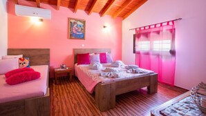A bedroom with a wooden ceiling, a bed with pink bedding, a nightstand, and a window with pink curtains. - Stergios Villa (Rhodes)