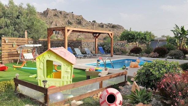 A backyard with a swimming pool, a wooden playhouse, and a covered seating area. - Stergios Villa (Rhodes)