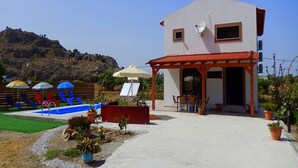 A building with a pool, outdoor seating, and a mountainous backdrop. - Stergios Villa (Rhodes)