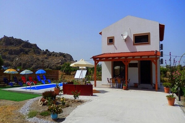 A building with a pool, outdoor seating, and a mountainous backdrop. - Stergios Villa (Rhodes)