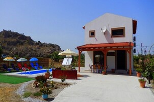 Un edificio con piscina, mobiliario exterior y montañas al fondo.