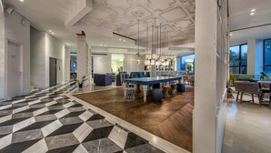 Eine großzügige Lobby mit Schachbrettmuster-Boden, einer zentralen Sitzecke und einer dekorativen Decke.