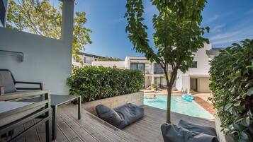 A modern outdoor patio with a pool, wooden deck, and seating area.