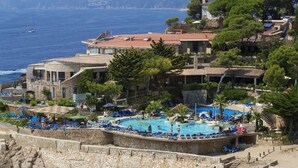 A coastal hotel with a swimming pool, multiple balconies, and a view of the sea. - Eden Roc (Sant Feliu de Guixols)