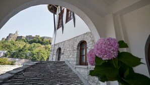 Un edificio de piedra con ventanas de arco y vista a un castillo en una colina.
