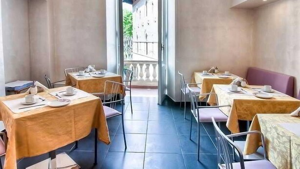 Ein Restaurant mit gedeckten Tischen, einem Balkon mit Geländer und Blick auf ein Gebäude.