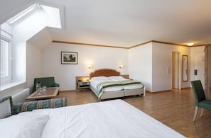 Ett hotellrum med en säng, ett skrivbord, en stol, ett nattduksbord och en tavla på väggen.