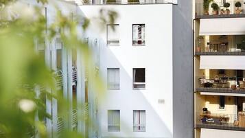 A modern multi-story residential building with balconies, large windows, and a rooftop garden.