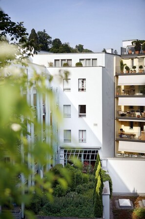 Ein modernes, mehrstöckiges Wohngebäude mit Balkonen, großen Fenstern und einem Dachgarten.