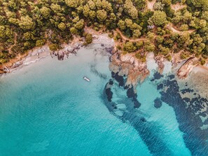 An aerial view of a coastal area with a boat on the water, surrounded by dense greenery and rocky terrain. - La Residence du Bailli (Rayol-Canadel-sur-Mer)