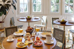 A breakfast setting with multiple tables, chairs, and a variety of food and drink items. - La Residence du Bailli (Rayol-Canadel-sur-Mer)