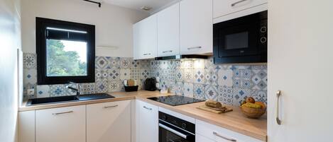 Una cocina moderna con armarios blancos, un microondas negro y un salpicadero de azulejos.