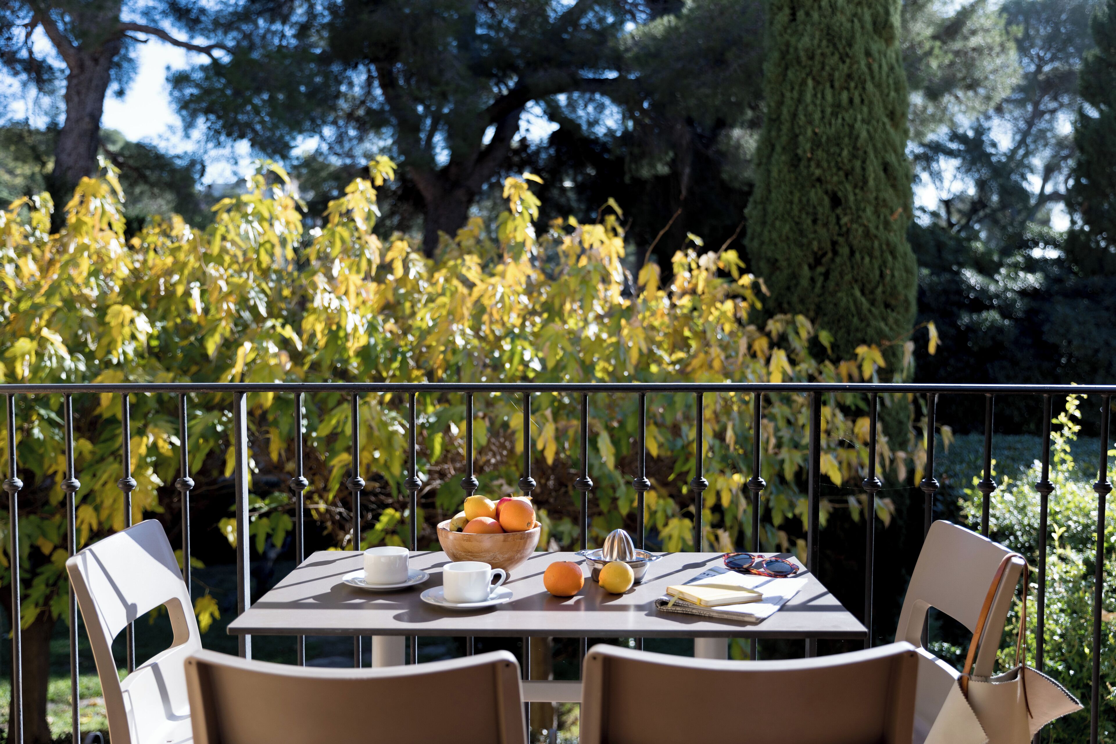A table set outdoors with a bowl of fruit, a cup, and a book.