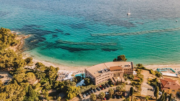 An aerial view of a coastal hotel with a pool, beach, and clear blue waters. - La Residence du Bailli (Rayol-Canadel-sur-Mer)