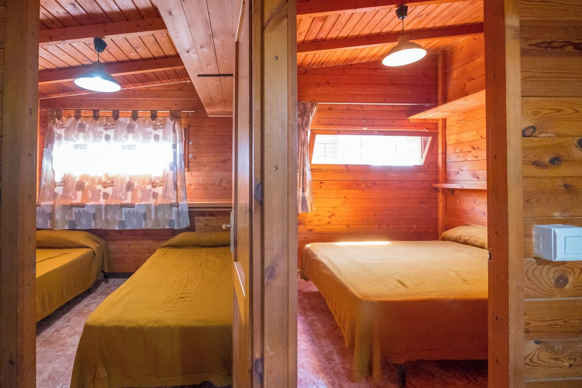 Una cabana amb dos llits individuals, parets de fusta i un sostre inclinat.