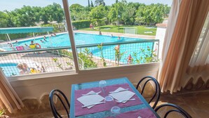 Une table dressée pour quatre personnes, avec vue sur une piscine et sur la verdure.
