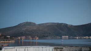 A coastal landscape with a mountain, a marina, and buildings in the background. - Bianco Hotel (Leros)