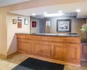 A reception desk with a dark countertop, framed pictures on the wall, and a fire extinguisher.