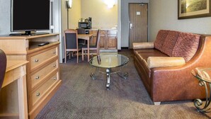 A hotel room with a flat-screen TV, a glass coffee table, a sofa, a desk with a computer, and a dining area. - Quality Inn & Suites Casper Near Event Center (Casper)