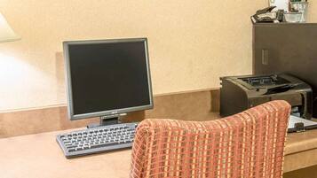 A reception desk with a computer monitor, keyboard, and a patterned chair.