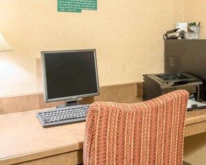 A reception desk with a computer monitor, keyboard, and a patterned chair.