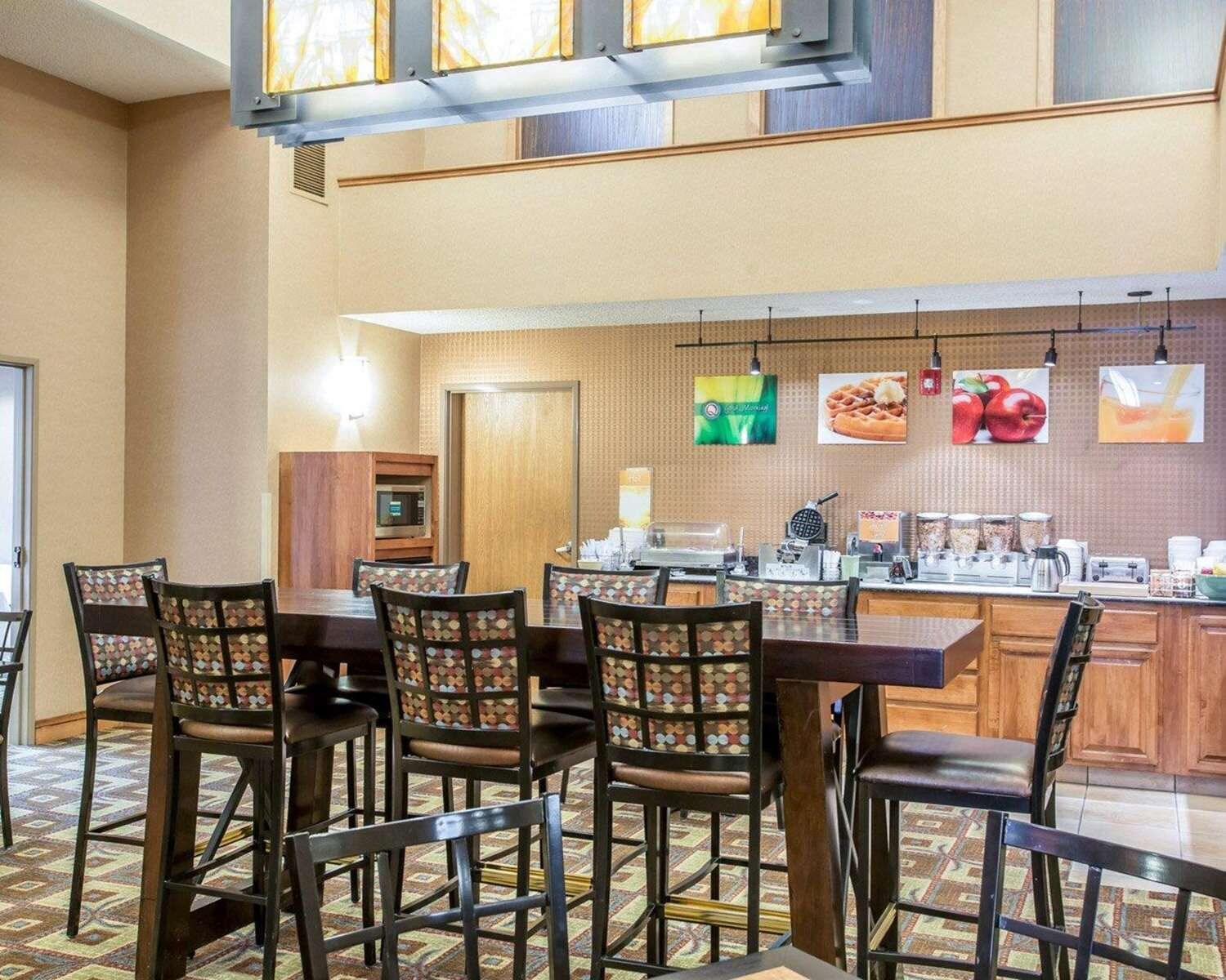 A hotel breakfast area with a buffet setup, including a microwave, coffee maker, and various food items.