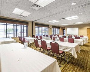 A conference room with tables and chairs, large windows, a projector screen, and a carpeted floor. - Quality Inn & Suites Casper Near Event Center (Casper)