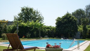A swimming pool with a wooden lounge chair and a flower pot. - Quinta De Santa Baia (Ponte de Lima)