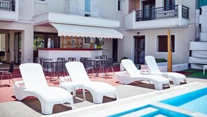 Zona de piscina amb gandules, bar i mobiliari exterior.