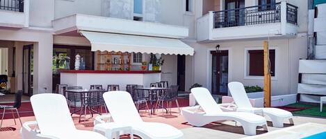A poolside area with lounge chairs, a bar, and outdoor seating.
