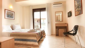 Un dormitori amb llit, escriptori, cadira i finestra amb cortines.