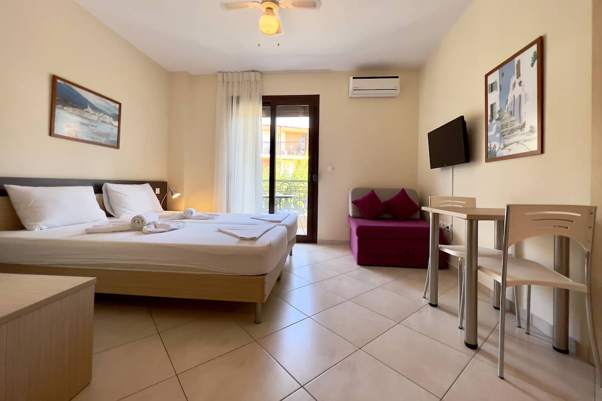 A hotel room with a bed, a desk, a chair, a TV, and a balcony.