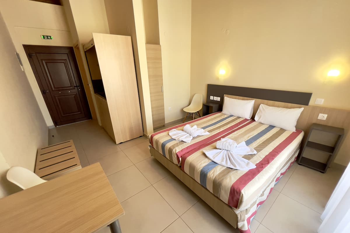A hotel room with a bed, bedside tables, a chair, and a desk.